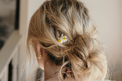 Messy blonde bun with flower in hair