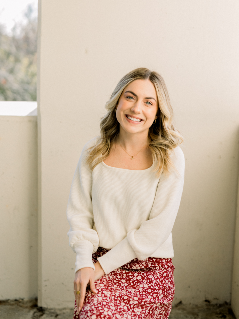 Jessica Sorensen sitting in a floral skirt and white top