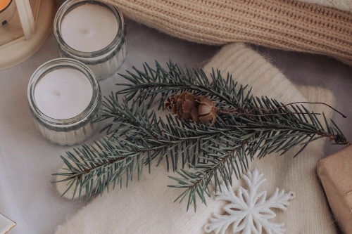 Candles, pine leafs and cones with cozy sweaters
